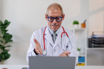 Male doctor working on laptop computer searching the information and using laptop at clinic desk....