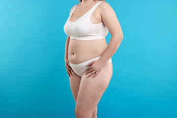 Weight loss. Plus size woman in underwear on light blue background, closeup