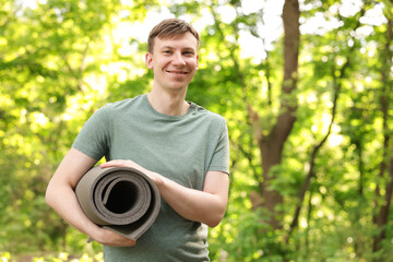 Young man with yoga mat in park