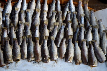 Rows of salted dried fish at a bustling market stall.