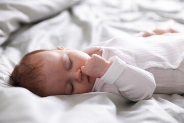 Cute newborn baby sleeping on bed, closeup