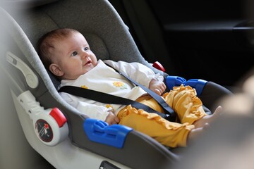 Cute little baby fastened in car seat