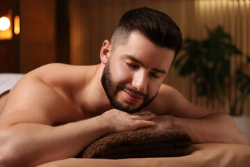 Handsome man lying on massage table in spa salon