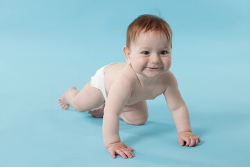 Cute little baby crawling on light blue background