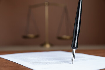 Signing notary document with fountain pen at table against brown background, closeup