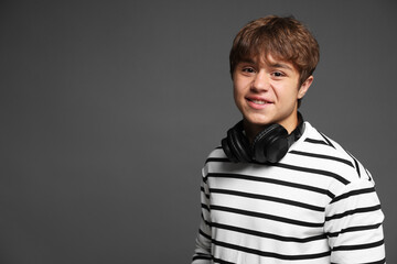 Portrait of smiling teenage boy with headphones on grey background. Space for text