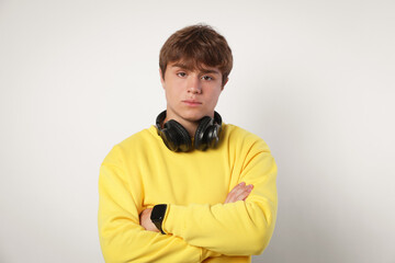 Portrait of teenage boy with crossed arms on light grey background