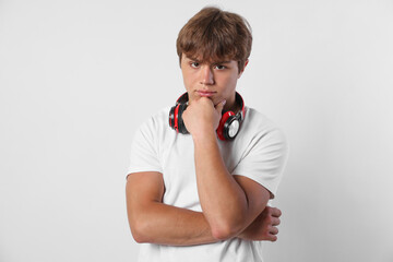Portrait of cute teenage boy with headphones on light grey background