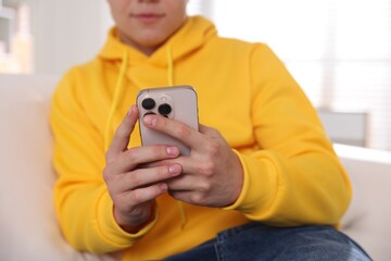 Teenage boy using smartphone at home, closeup