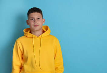 Portrait of teenage boy on light blue background, space for text