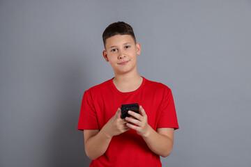 Teenage boy with smartphone on grey background