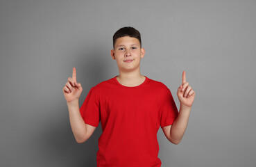 Teenage boy pointing at something on grey background