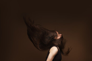 Teenage girl with healthy long hair on brown background