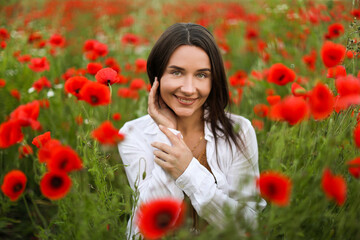Portrait of smiling woman among red poppy flowers in wildflower meadow