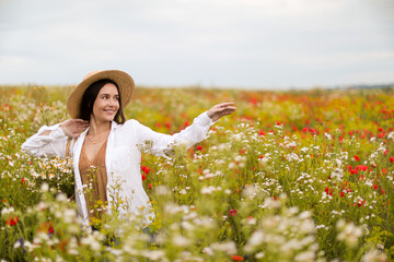 Smiling woman in hat walking in wildflower meadow