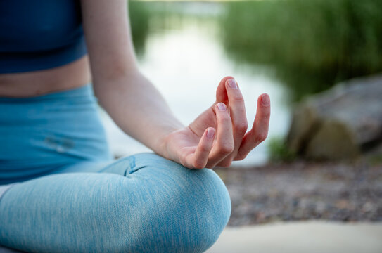 woman's hand in meditation mudra during yoga by summer lake