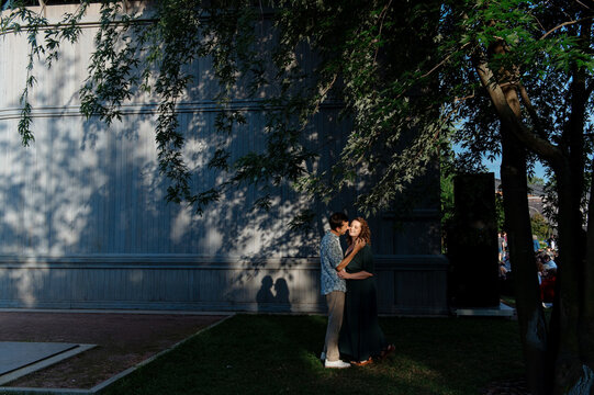 Couple enjoys romantic moment under trees in evening light