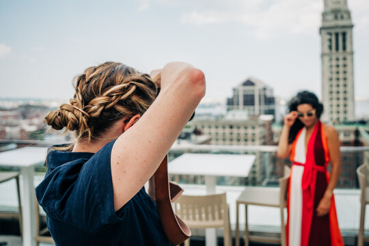 Photographer aims camera at model on a rooftop with city skyline