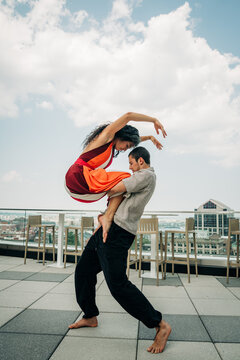 Barefoot dancers embrace in rooftop lift with city view