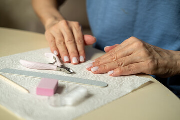 Nail care at home, close-up manicure. Using cuticle nippers, a nail file, a sanding pad, a brush and an orange stick.