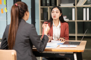 Two Asian businesswomen have a meeting in the office.
