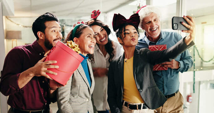 Christmas, business people and group selfie in office for funny photography with gift. Xmas picture, friends and happy workers with holiday spirit, December celebration or social media post at party - Powered by Adobe