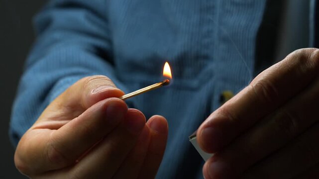 A close-up of a flaming match in the guy&rsquo;s hands.
Flammable objects and starting a fire with a wooden match.
Bright blazing fire lit by a match