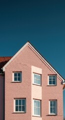 Pink house with windows against a clear blue sky