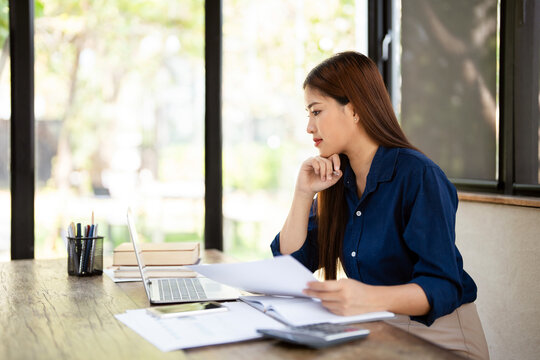 Workaholic woman on weekend do work at home sit at desk, self-employed female hold documents check data using laptop looks at screen working, usage of e-banking