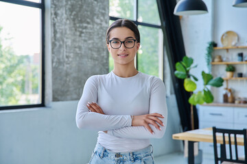 Portrait of confident successful teenage girl posing with crossed arms at home