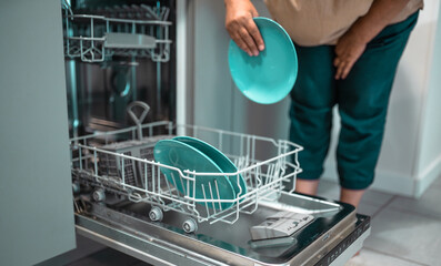 Woman loads dishwasher. Everyday life concept.