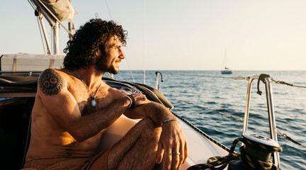 Sailor enjoying a relaxing sunset view from his sailboat during summer holidays
