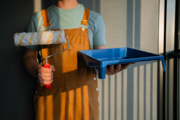 Professional painter stands with a paint roller and tray, ready for work. The image captures the...