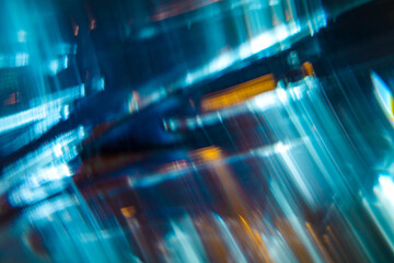 A dynamic abstract image featuring streaks of blue and teal light with motion blur and hints of orange highlights.