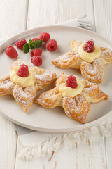 Puff pastry cake in the shape of a flower with custard cream and fresh raspberries close-up in a plate on the table. Vertical