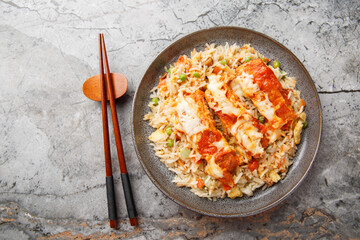 Baked Pork Chop Rice is a Hong Kong classic dish egg fried rice, seared pork and a rich tomato sauce rest under cheese closeup in a plate on the table. horizontal top view from above
