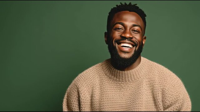 Happy young African man with beard against solid green backdrop positive expression, casual style