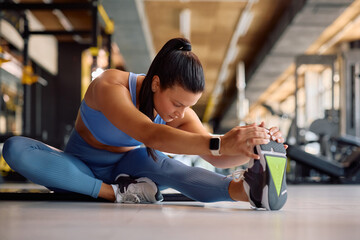 Young athlete stretching her leg while working out in health club.