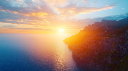 Dramatic sunset over a coastline.  Rocky cliffs meet a tranquil ocean under a vibrant sky filled with warm hues of orange and yellow
