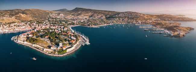 Aerial panorama of Foca, Turkey, historic coastal town with marina, fortress walls and red rooftops on the Aegean Sea