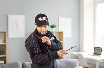 Police officer communicating and talking via wireless radio while investigating a crime scene at...