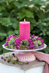 Arrangement mit einer Kerze und Blumenkranz mit Hortensienblüten, Wilder Möhre, Feldthymian,...