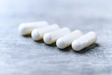 Beta-alanine capsules. Bodybuilding food supplements on wooden background. Soft focus. Close up....