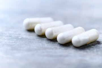 Beta-alanine capsules. Bodybuilding food supplements on wooden background. Soft focus. Close up....