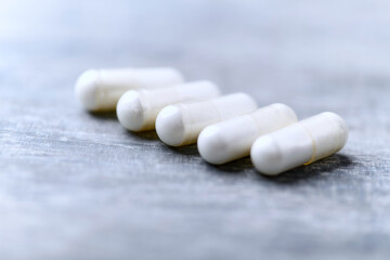 Beta-alanine capsules. Bodybuilding food supplements on wooden background. Soft focus. Close up....
