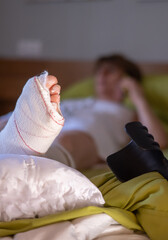 Woman resting in bed with a broken foot in a cast and crutches nearby, highlighting the challenges...