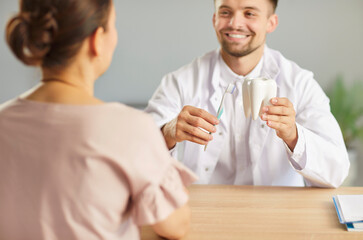 Young male doctor dentist in white medical uniform holding dental toy tooth with toothbrush in...