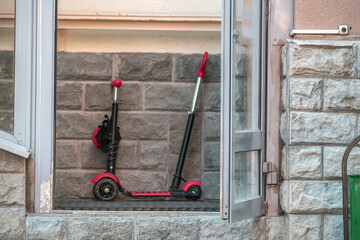 A child's scooter is parked on the porch on a summer day