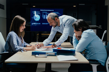 Senior executive mentoring junior colleague in modern office with presentation screen