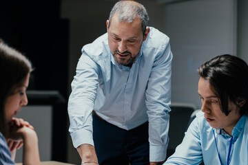 Senior executive mentoring junior colleague in modern office with presentation screen